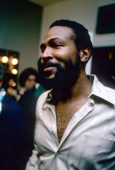 a man with a beard and white shirt standing in front of a group of people