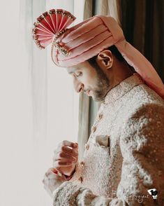 a man wearing a pink hat standing next to a window with a red fan on it's head