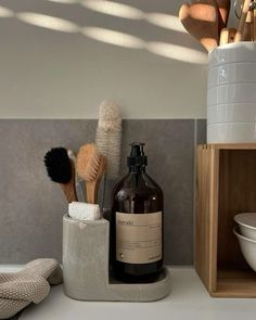 there is a bottle and two brushes in the holder on the counter next to each other