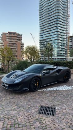 a black sports car parked in front of a tall building