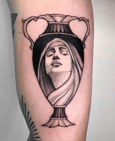 a woman's face in a vase tattoo on the right arm and shoulder area