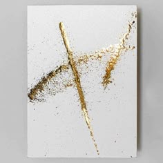 a white square with gold paint splattered on it