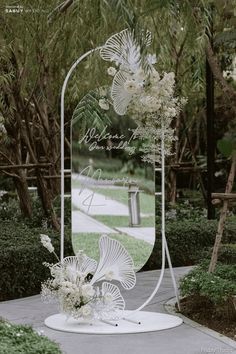 an outdoor area with flowers and plants on the ground in front of a large mirror