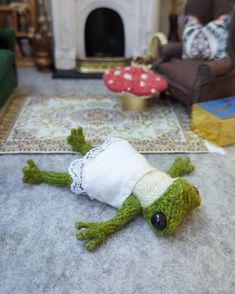 a stuffed frog is laying on the floor in front of a fire place and couch