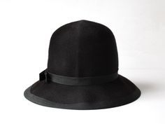 "A beautiful 1950s Henry Pollack jet black felted wool hat. The deep crown and downward sloping brim are trimmed with grosgrain ribbon and a single ribbon bow is attached at the side.  Banded interior.  LABEL Henry Pollack New York - Starfire  100% Wool - Melange Blend Felt Union Made - USA  MEASUREMENTS  Circumference 23\" Crown 5\" Brim 3\" EXCELLENT CONDITION  Beautiful inside and out. No noticeable signs of wear.  ------------------------------------------ USPS SHIPPING  All hats ship free o Evening Wool Cloche Felt Hat, Classic Black Wool Cloche Hat, Classic Fur Felt Hat For Evening, Vintage Black Fur Felt Fedora, Classic Evening Fur Felt Hat, Black Vintage Fur Felt Fedora, Wool Cloche Hat For Evening, Classic Black Fur Felt Cloche Hat, Evening Wool Cloche Hat With Curved Brim