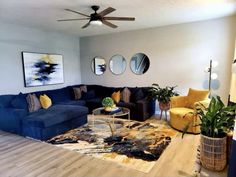 a living room with blue couches, yellow chairs and a rug on the floor