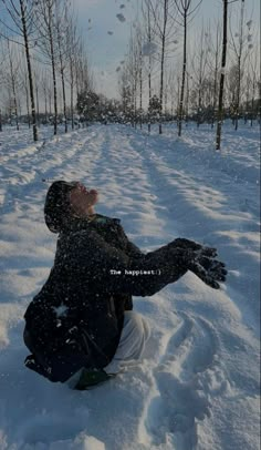 a man sitting in the snow with his arms outstretched and eyes closed, looking up into the sky