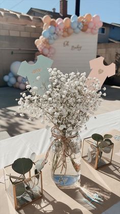 a vase filled with baby's breath sitting on top of a table covered in balloons