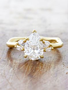 a yellow gold engagement ring with a pear shaped diamond