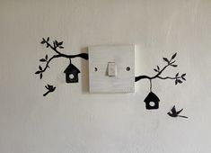 a light switch cover with birds and birdhouses on it's side, hanging from a tree branch