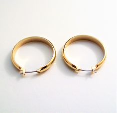 Monet wide band classic hoop surgical steel post pierced stud earrings vintage polished smooth reflective domed open large dangle rings. In excellent never worn still on the card condition. Measures 1 1/8 of an inch wide and long. Classic Metal Hoop Earrings For Anniversary, Dangle Rings, Retro Gold Round Clip-on Earrings, Vintage Round Brass Clip-on Earrings, Vintage Round Clip-on Earrings With Polished Finish, Vintage Yellow Gold Round Clip-on Earrings, Gold-tone Brass Hoop Earrings With Polished Finish, Costume Earrings, Stud Earrings Gold