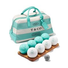 a blue and white duffle bag sitting on top of a wooden tray filled with balls