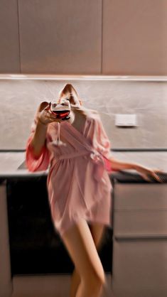 a woman in a pink dress holding a glass of wine