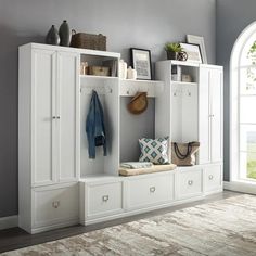 a room with white cabinets and shelves filled with shoes, purses and other items