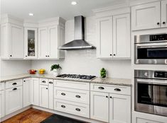 a kitchen with white cabinets and stainless steel stove top oven in the center, along with hardwood flooring