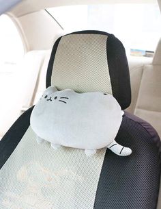 a cat pillow sitting in the back seat of a car with it's eyes closed