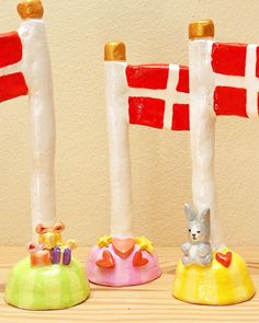 three small candles sitting next to each other on top of a wooden table with flags in the background