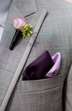 a man wearing a suit and tie with a flower in his lapel pocket,