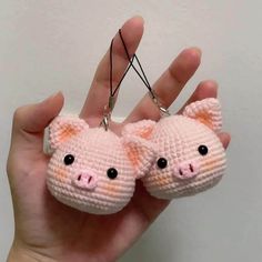 two small crocheted pig keychains are being held in the palm of someone's hand