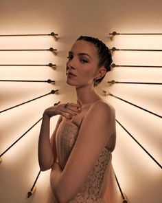 a woman standing in front of a wall with lights on it