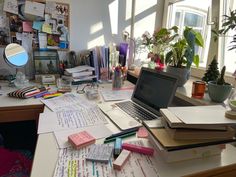 a laptop computer sitting on top of a desk covered in lots of papers and sticky notes