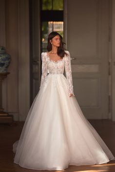 a woman in a white wedding dress standing on a wooden floor with an open door