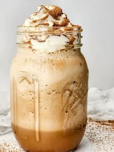 an iced drink with whipped cream and cinnamon in a mason jar on top of a table