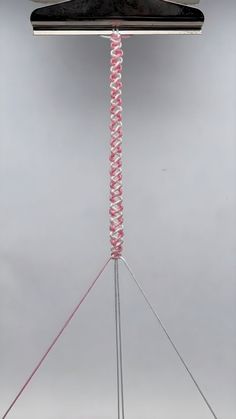 a piece of clothing hanging from a clothes hanger with pink and white yarn on it