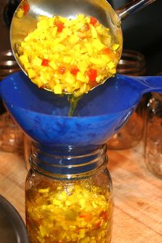 a glass jar filled with yellow and red condiments on top of a wooden table