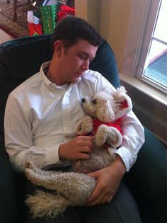 a man sitting in a chair holding a teddy bear and wearing a red bow tie