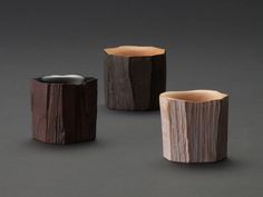 three wooden vases sitting next to each other on a gray surface, one is made out of wood