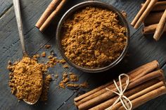 cinnamon sticks and powder in a bowl on a wooden table next to some cinnamons