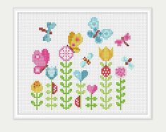 a cross stitch pattern with colorful flowers and butterflies on the front, in white frame