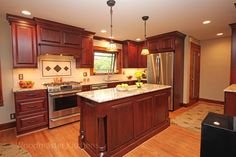 a large kitchen with wooden cabinets and stainless steel appliances in the center, along with hardwood flooring