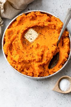 a bowl filled with mashed sweet potatoes on top of a table next to a spoon