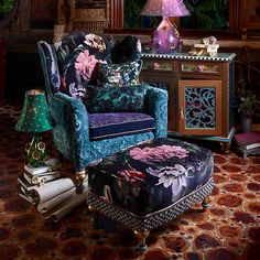 an ornately decorated chair and ottoman in front of a table with lamps on it