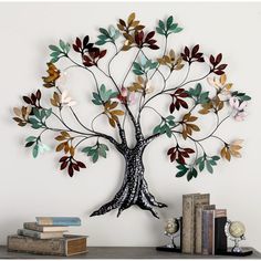 a metal tree sculpture on top of a wooden table next to books and a clock