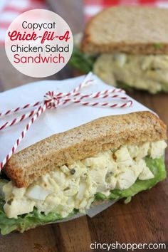 chicken salad sandwich cut in half on a wooden cutting board with red and white twine