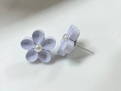 two white flowers with pearls on them sitting next to each other in front of a white background