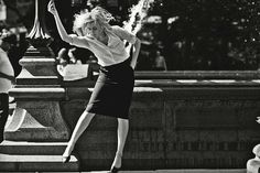 a black and white photo of a woman jumping in the air with a tennis racket