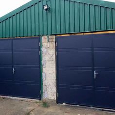 two blue garage doors in front of a brick wall and green metal roof on an industrial building