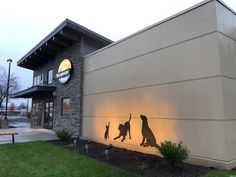 a dog and cat silhouettes on the side of a building with lights in front of it