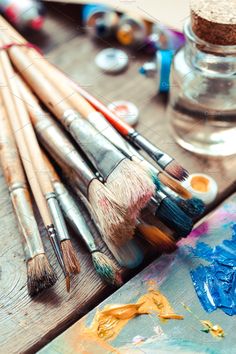 an assortment of paintbrushes and brushes on a wooden table