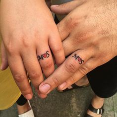 two people holding hands with tattoos on their fingers and the word mom written in small letters