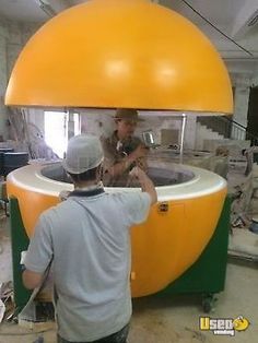 two men working on an object in a room with large yellow balls and green trimmings