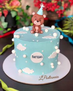 a blue birthday cake with a teddy bear on top