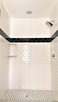 a white tiled shower with black and white tile on the floor, walls and ceiling