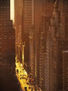 an aerial view of the city with tall buildings and cars driving down it at sunset