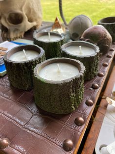 four candles sitting on top of a wooden table next to a skull and other items