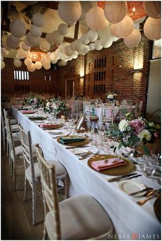 a long table is set with plates and place settings for an elegant wedding reception at the brick building